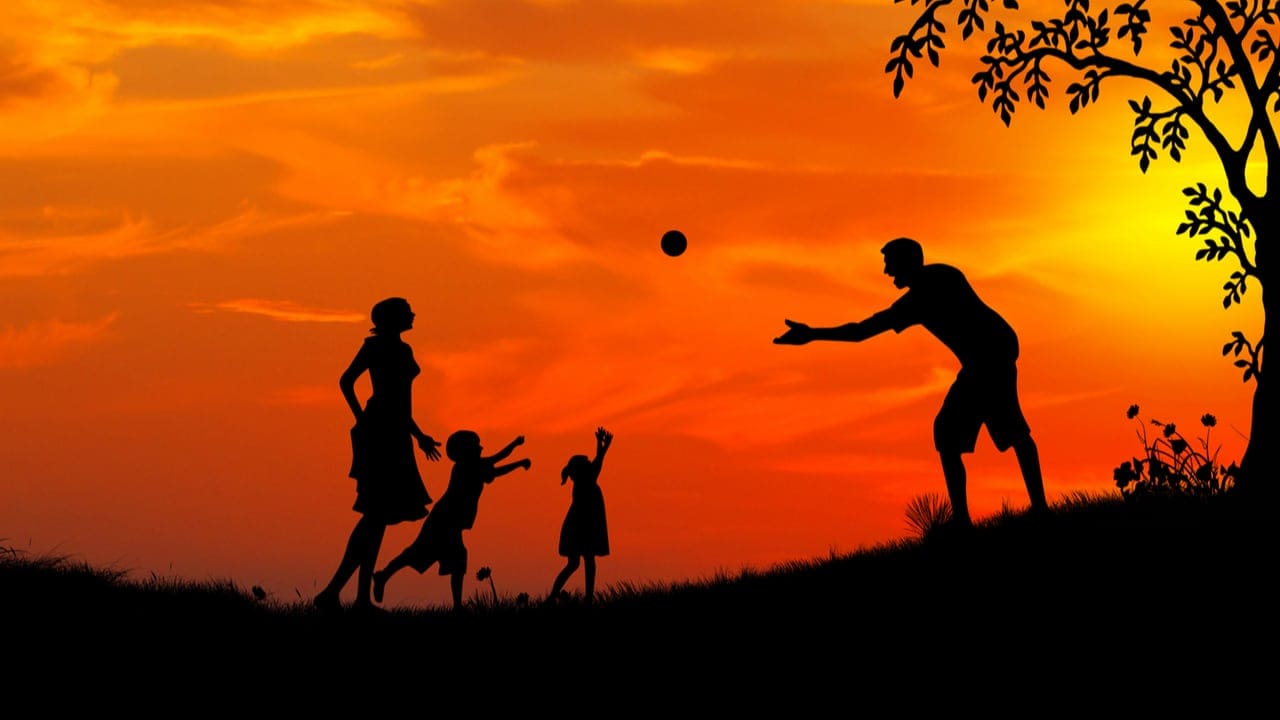 A family playing together silhouetted against a red sunset - family playtime