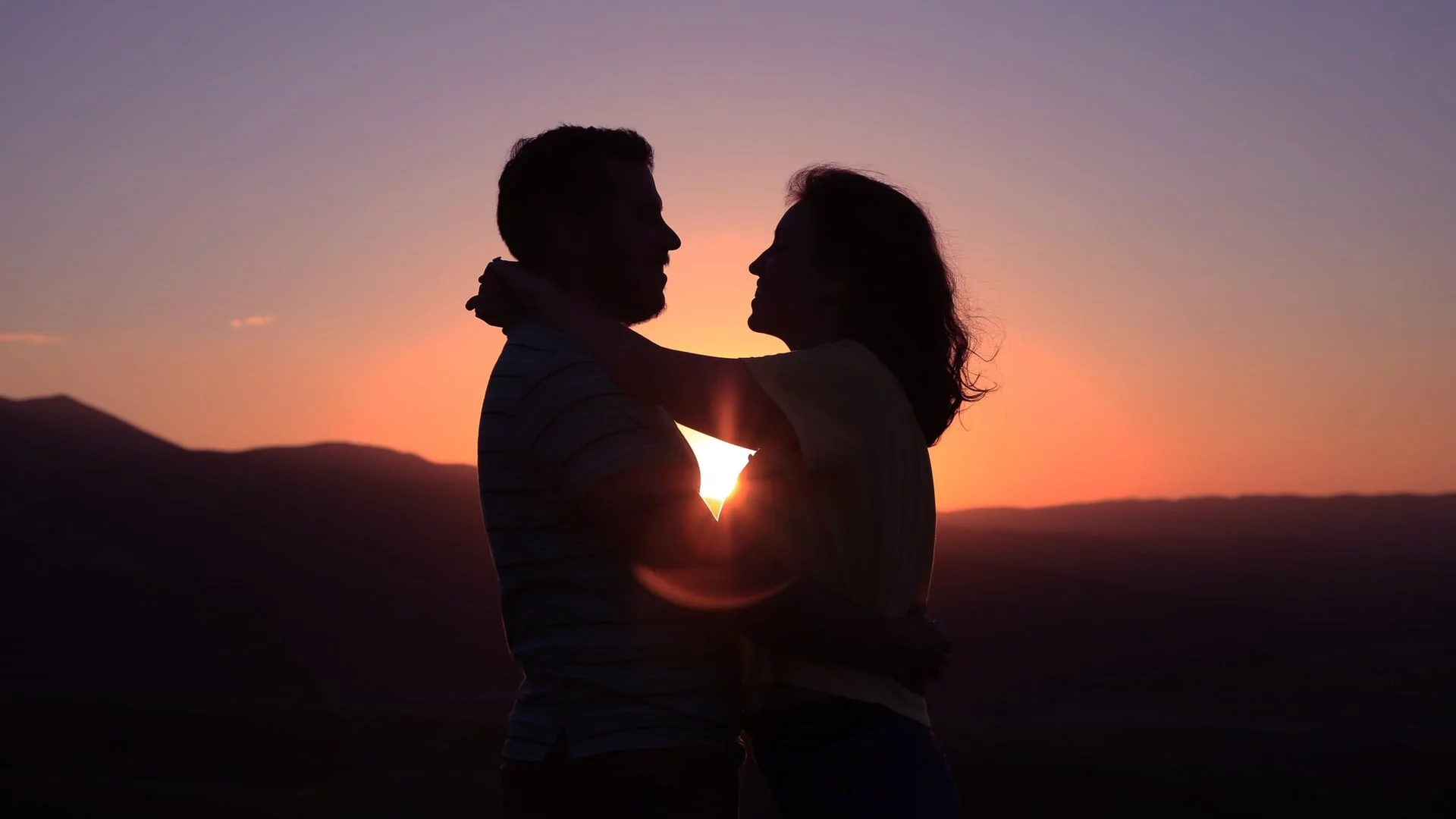 a couple holding each other affectionately silhouetted against a sunset - premarital counselling