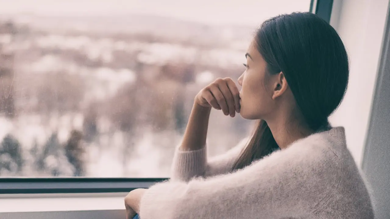 A thoughtful woman looking out of a window - signs of depression